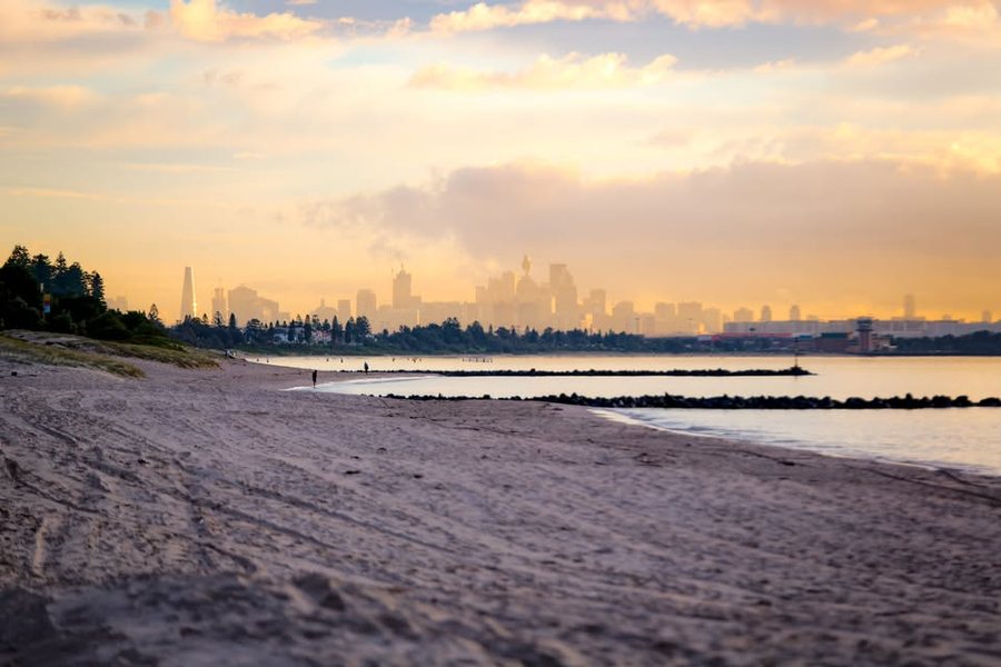 A beach at dusk with the Sydney skyline in the distance