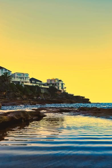 Coastal houses above a rock pool at sunset