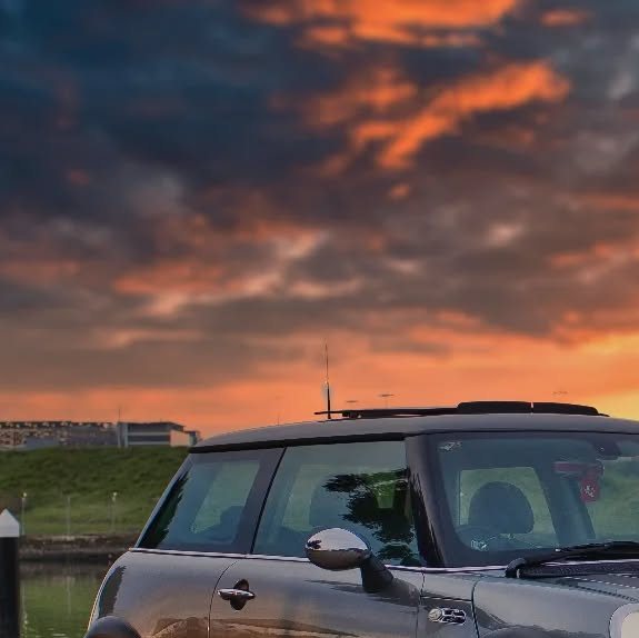 A Mini Cooper S in a car park under a dramatic evening sky